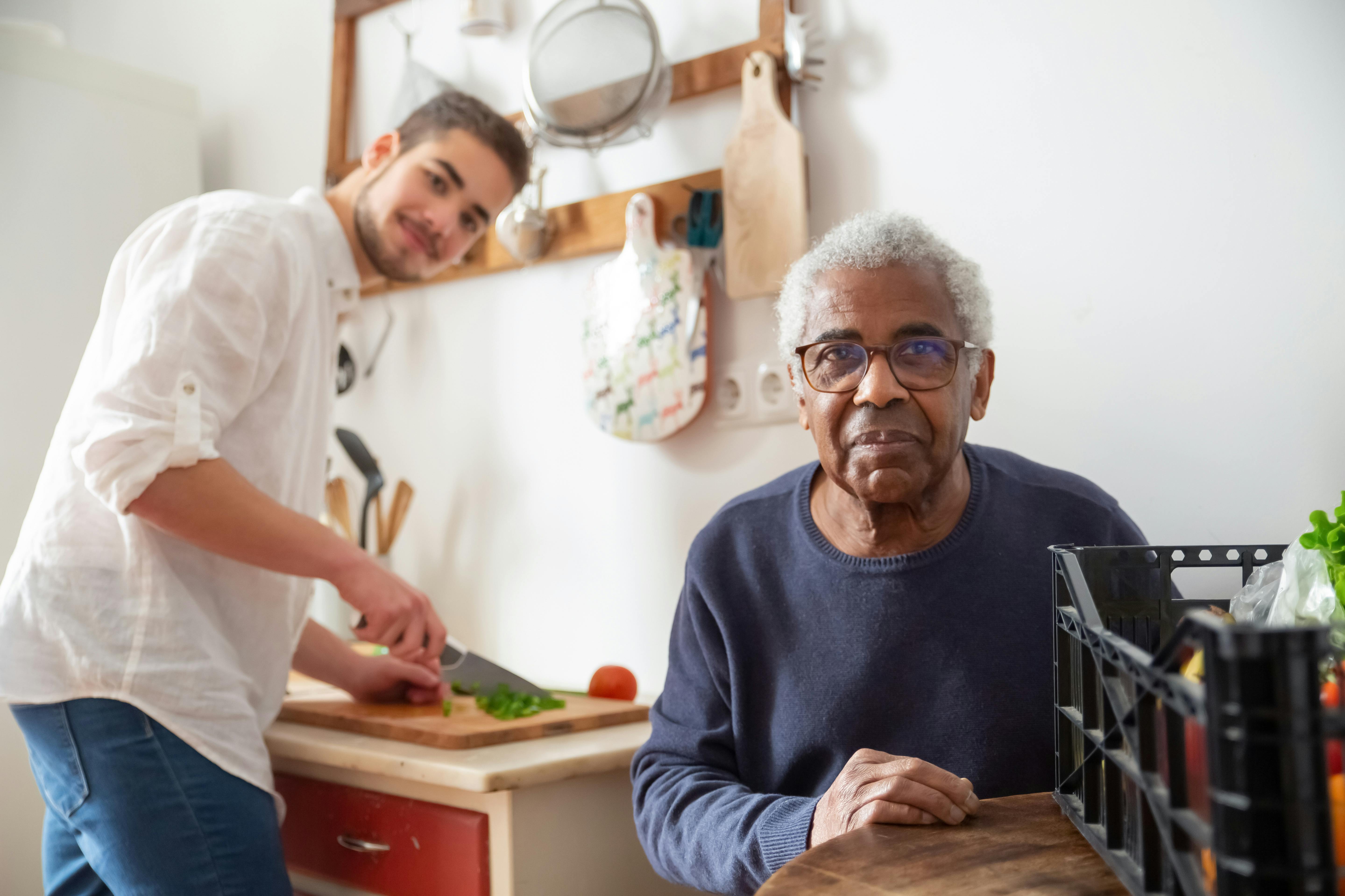 Caregiver and senior preparing food in kitchen