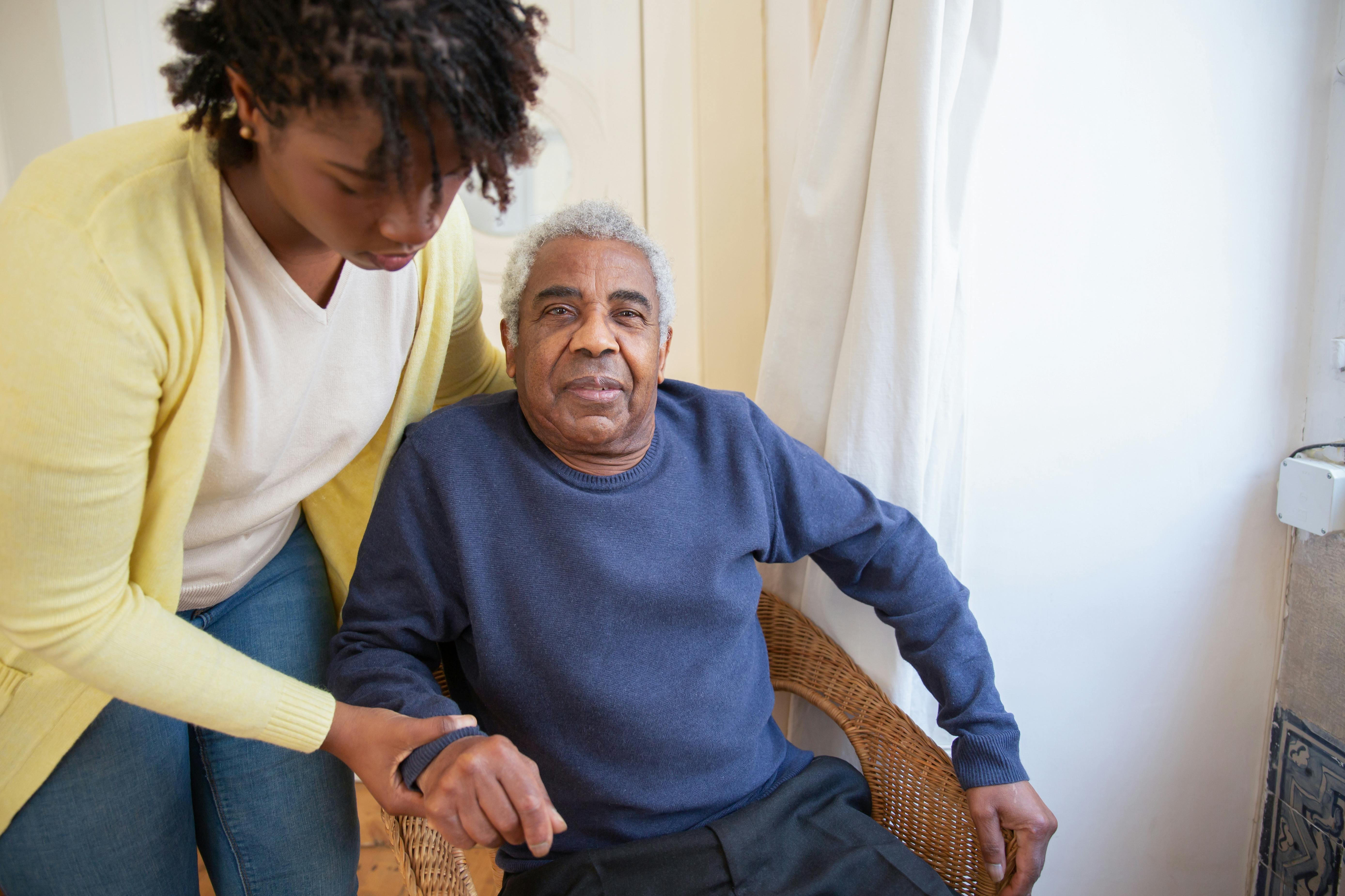 Caregiver assisting senior to stand