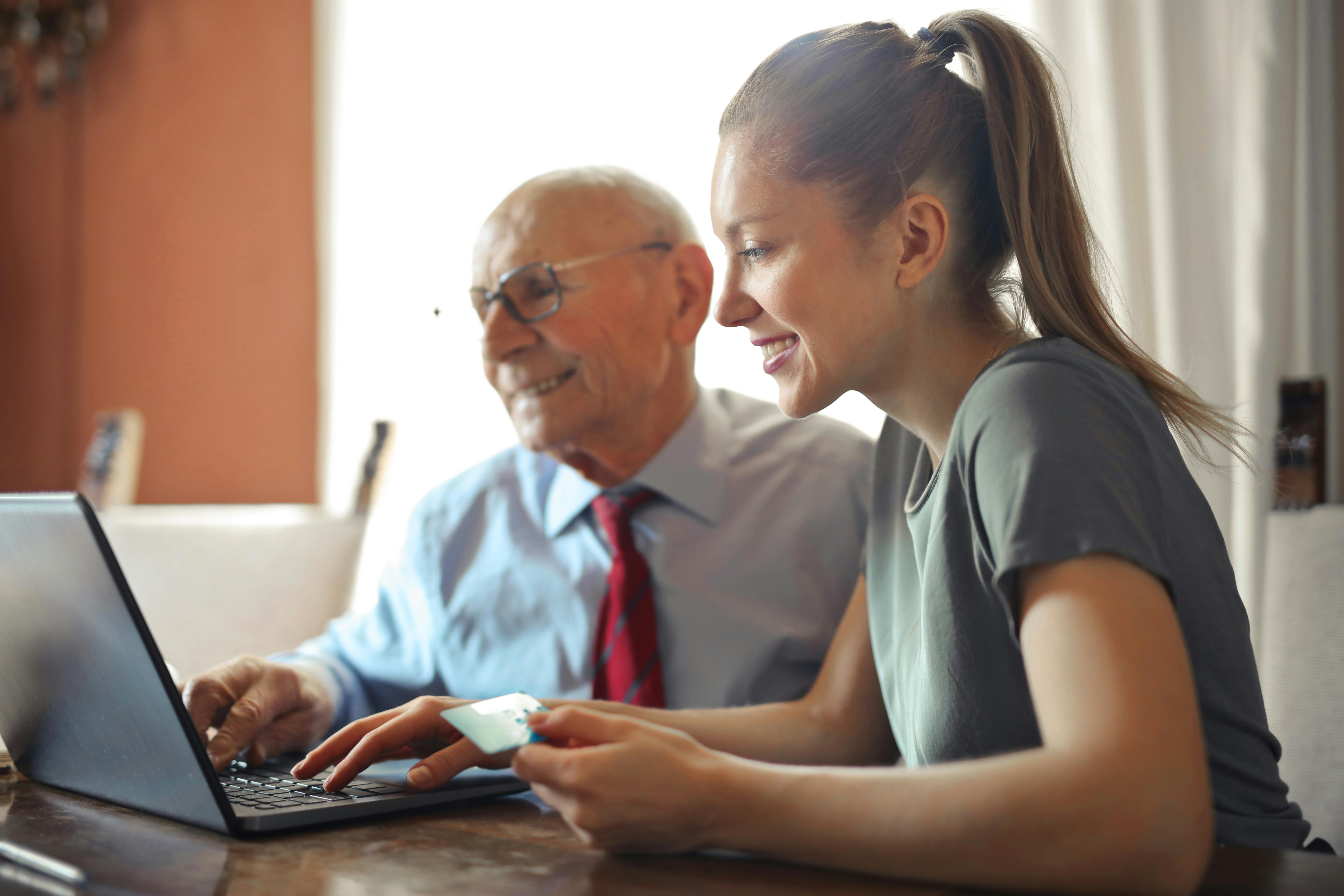 Caregiver and senior interacting with laptop